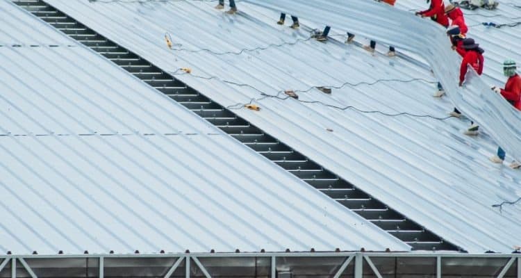 Roofing crew performing maintenance repairs on a commercial metal roof