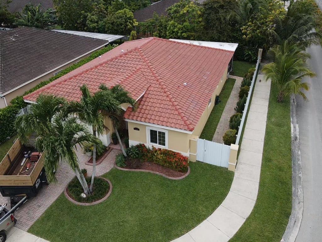 Aerial view of a pristine South Florida residential home featuring a premium red concrete tile roof